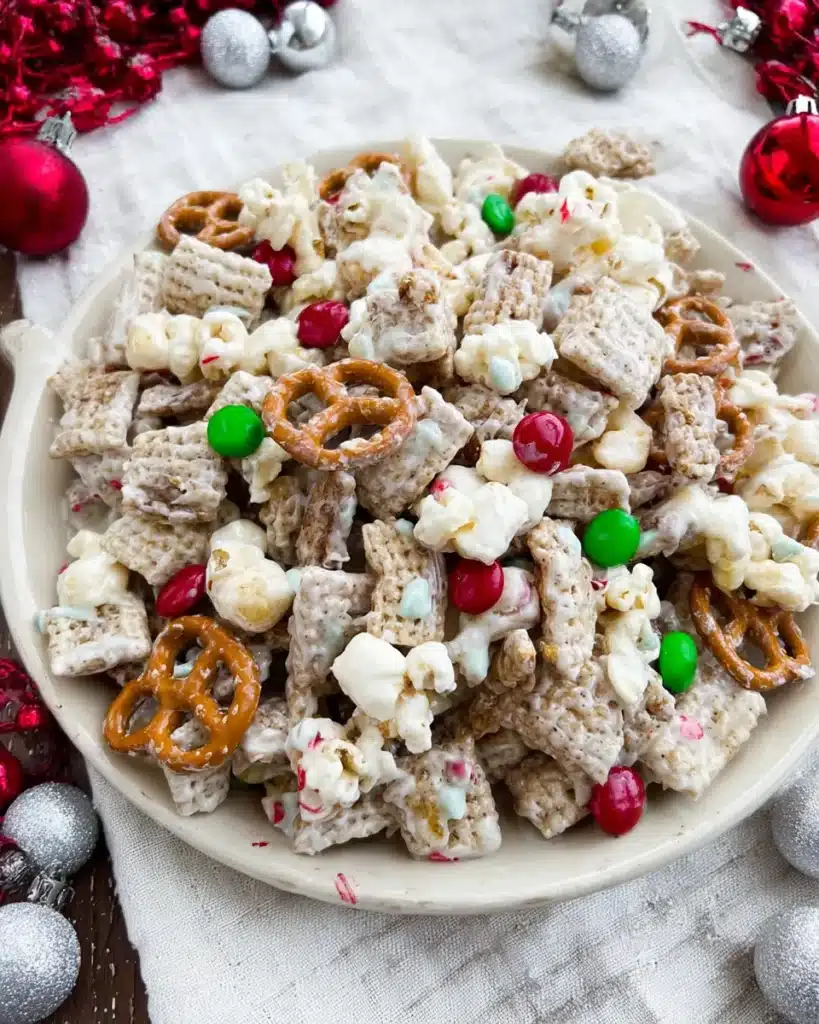 Festive bowl of reindeer chow with white chocolate, pretzels, popcorn, and Christmas candies