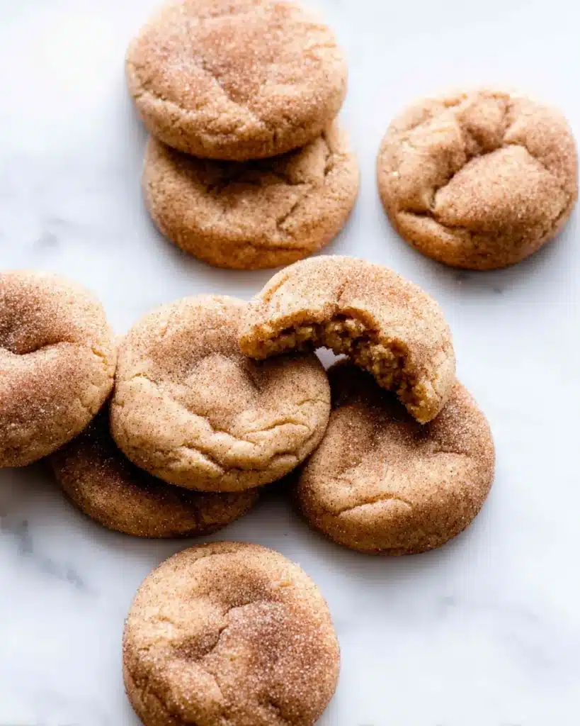 Close-up of snickerdoodle cookies with cinnamon sugar topping on marble surface.