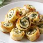 Golden spinach dip puff pastry pinwheels on a white plate