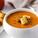 Creamy tomato basil soup with croutons in a white bowl