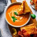 Creamy tomato bisque soup with grilled cheese sandwich and basil garnish