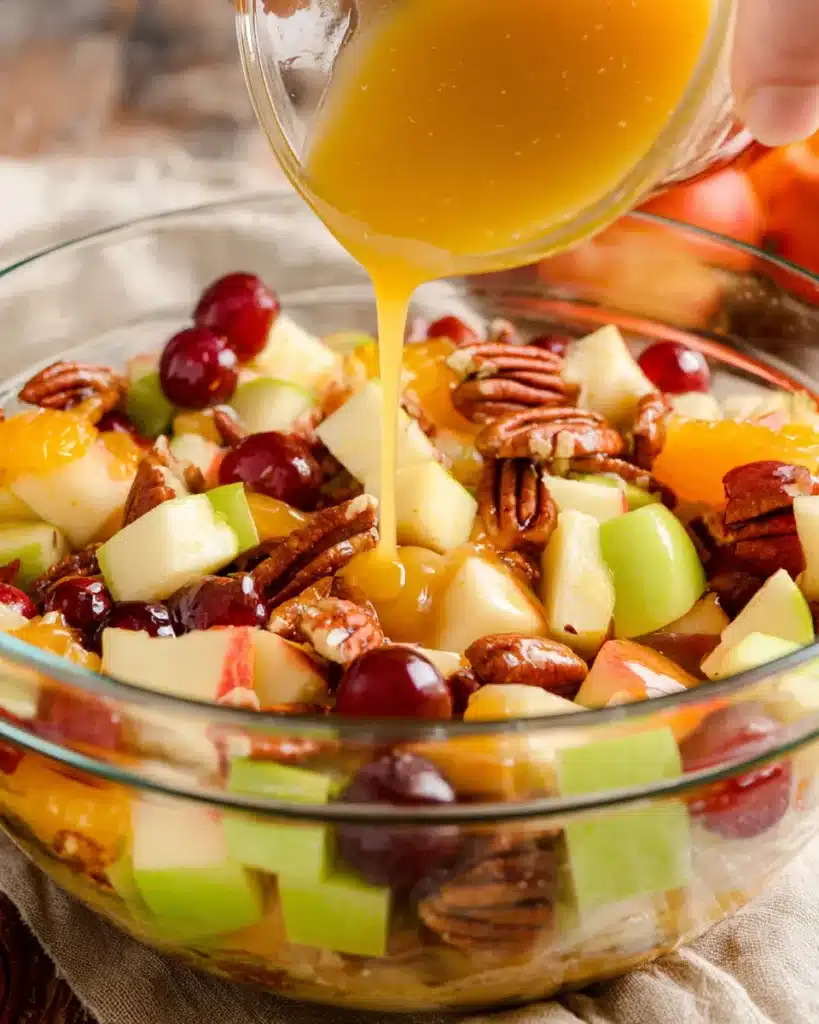Pouring citrus spice dressing over Thanksgiving fruit salad