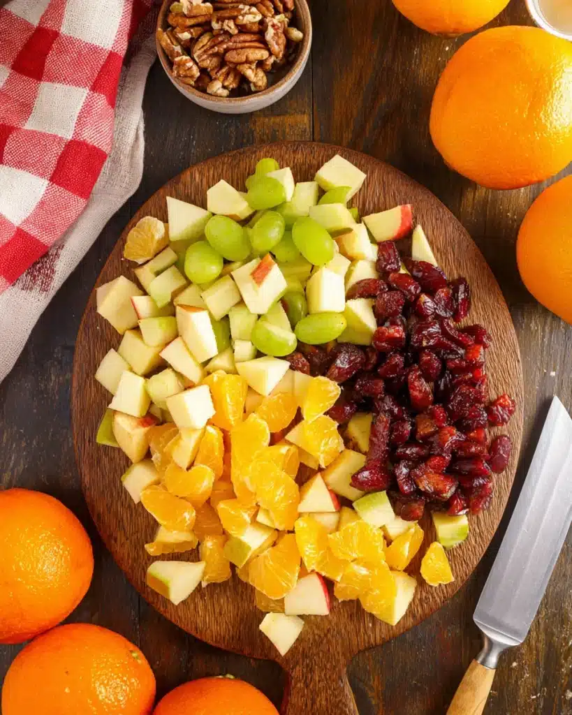 Chopped apples, oranges, grapes, and cranberries on a wooden board for fruit salad