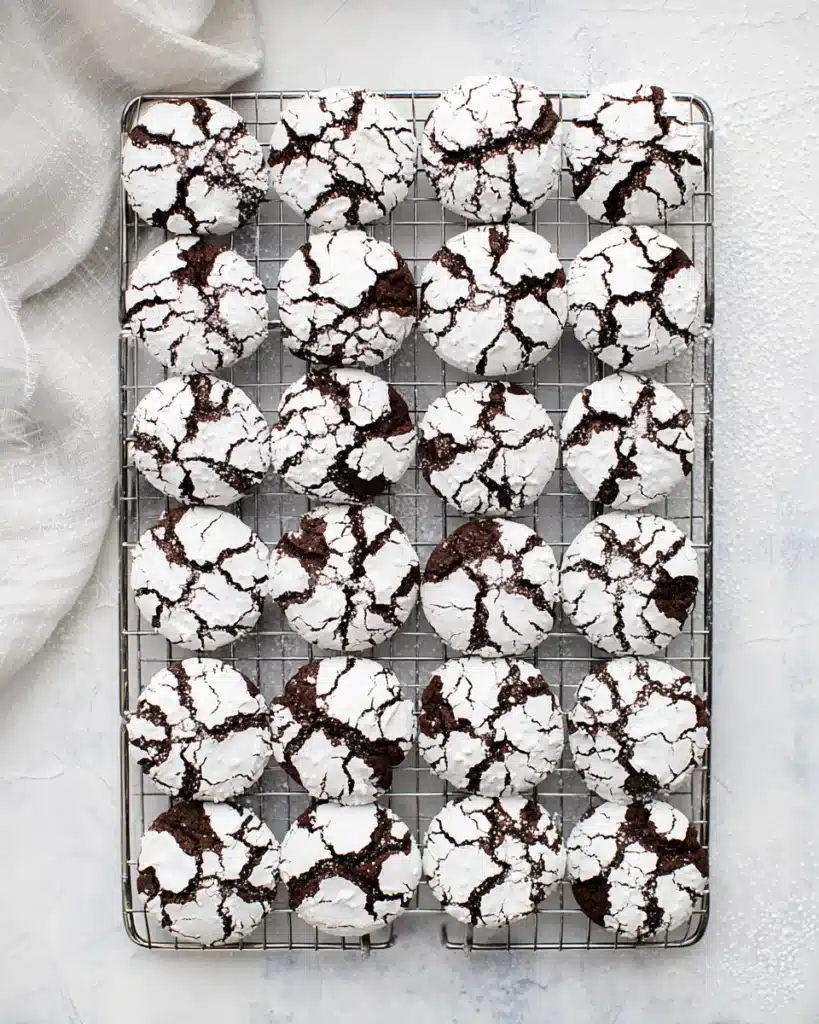 Overhead view of chocolate crinkle cookies on cooling rack with powdered sugar