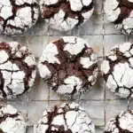 Freshly baked chocolate crinkle cookies with powdered sugar cracks on cooling rack