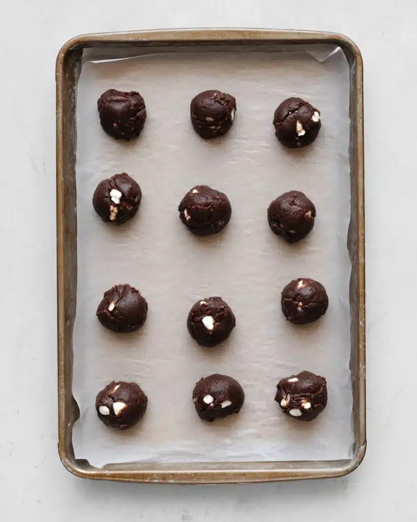 Hot chocolate cookie dough balls on parchment-lined baking tray