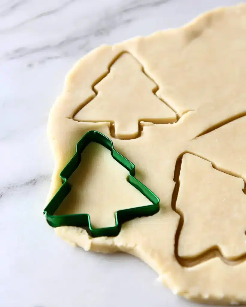 Vegan sugar cookie dough with Christmas tree cutter on marble surface